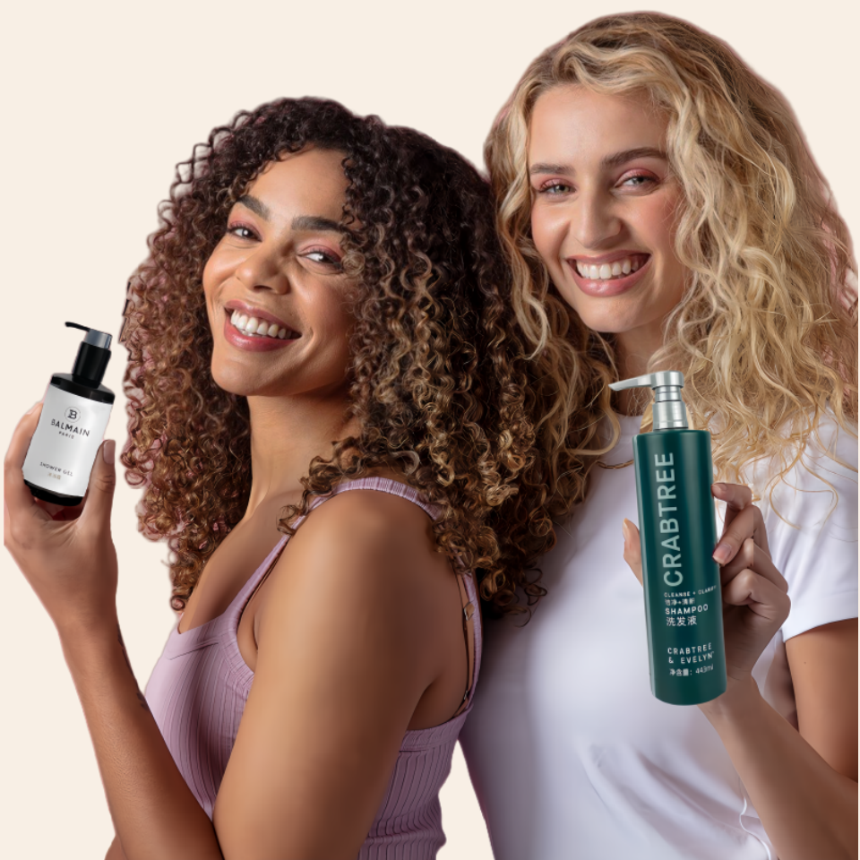 Two ladies each holding a bottle of toiletries